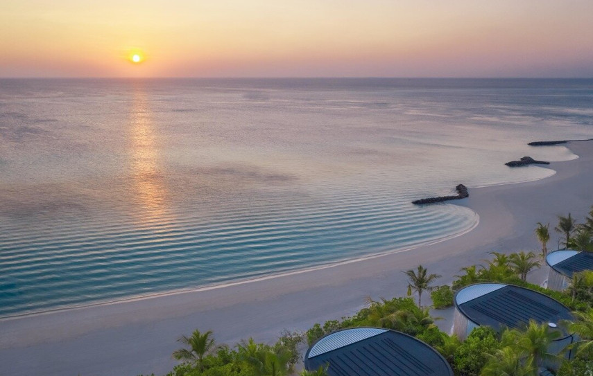 Traumhafter Sandstrand mit Blick auf die über dem Meer untergehende Sonne